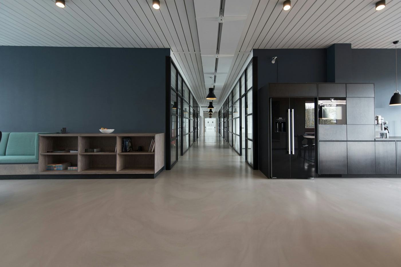 Interior contemporâneo em open space, com armários escuros e pavimento claro